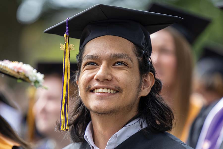 A 2024 graduate smiles while looking up at the stage.