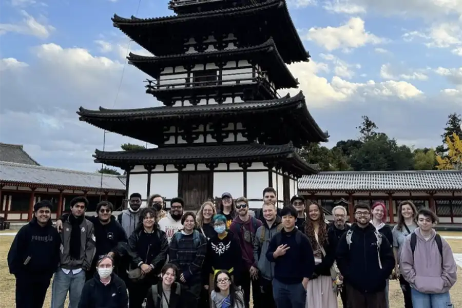 A group of students stand in front of a building in Japan.