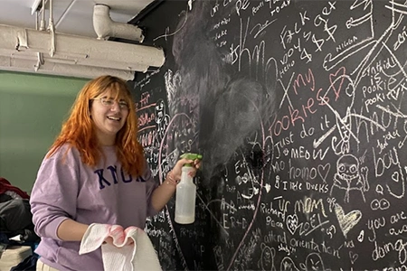 student cleans chalk board in the Knox Share Shop