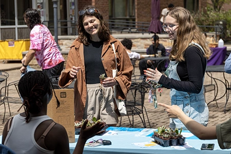 students interact with students hosting a table with plants