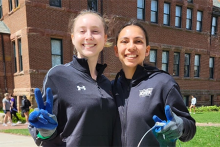 smiling students pose while wearing gloves for trash pickup day
