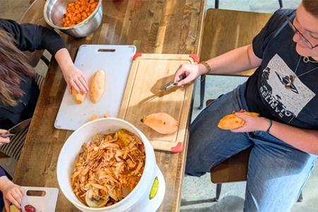 students peel sweet potatoes, saving the peels in a bucket