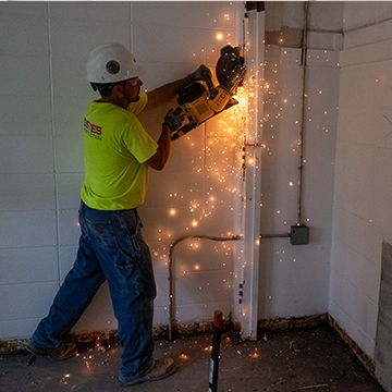 Sparks fly as a construction worker drills into a wall on the Knox campus