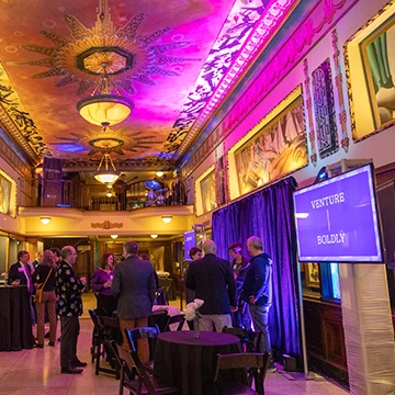 Alums and friends stand at the St. Louis Venture Boldly event, talking with each other. 