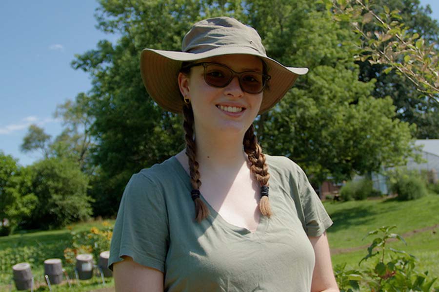 student wearing hat and sunglasses in a field